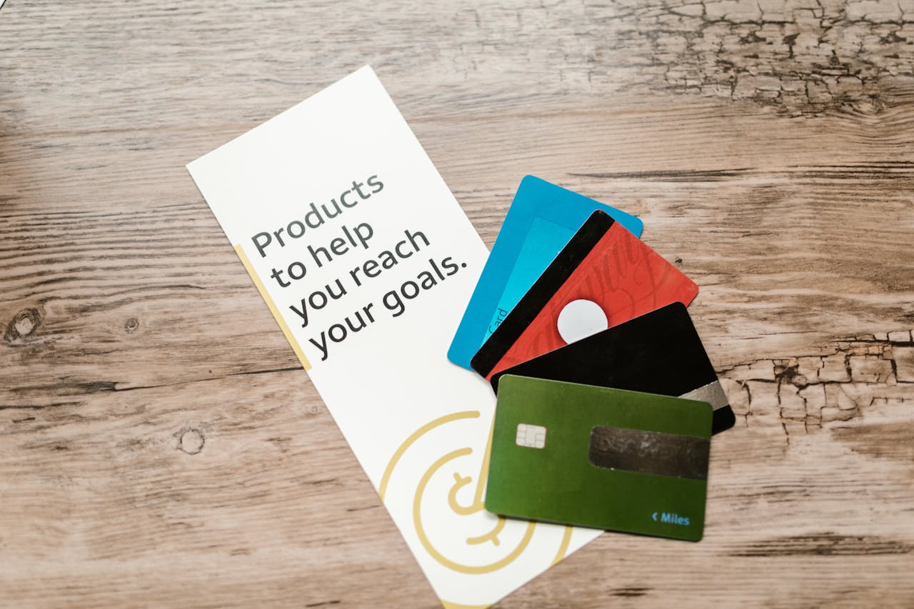 Assorted credit cards on a wooden table next to a leaflet with motivational text about financial goals.